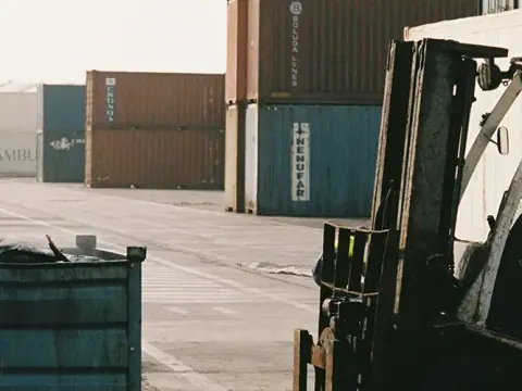 Forklift beside shipping containers at a logistics yard